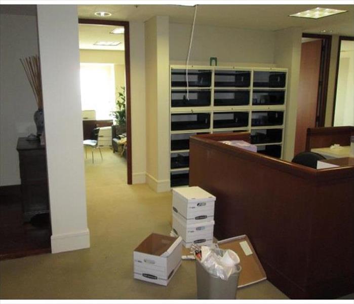 cartons and boxes on floor of office, bookcase in back